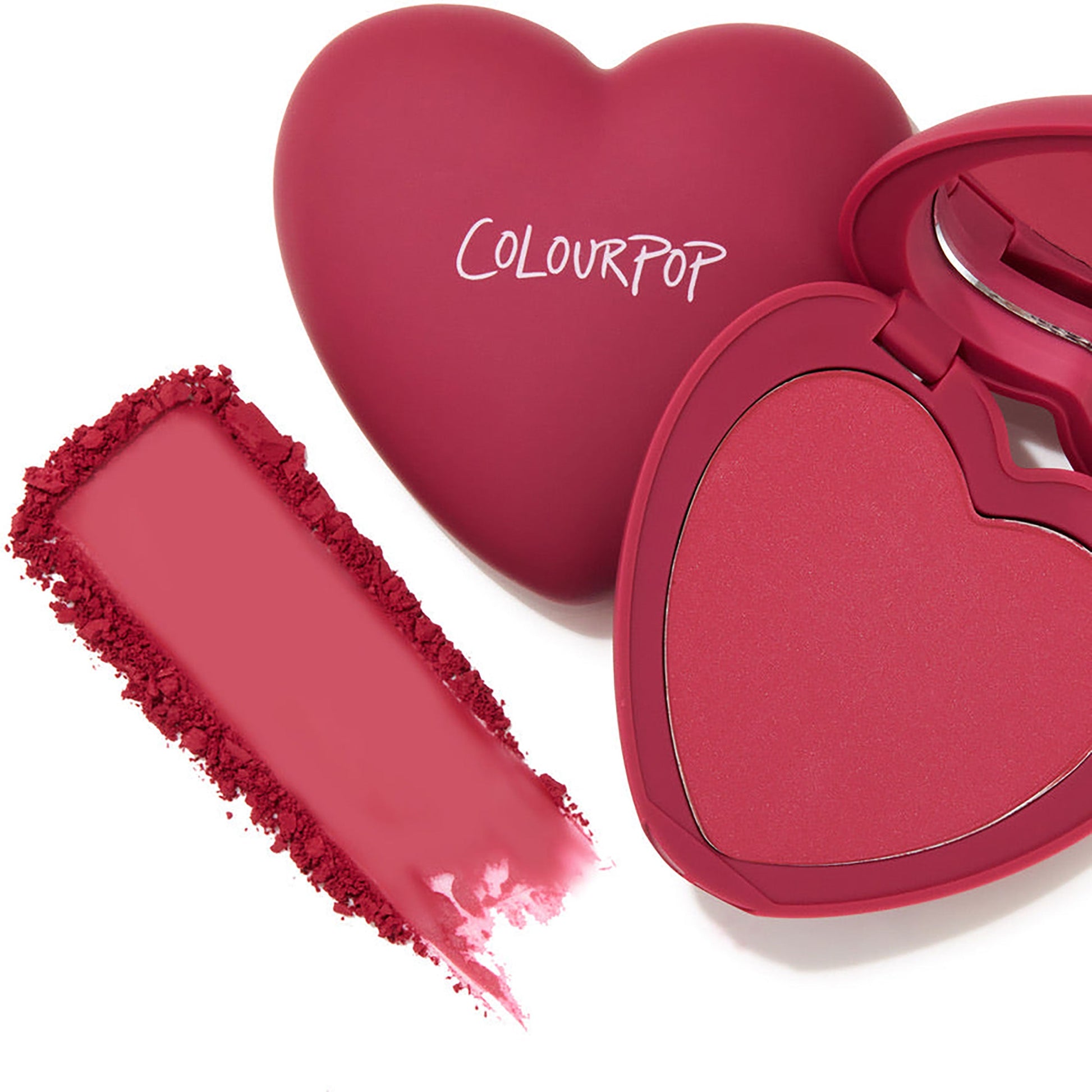 Heart-shaped ColourPop Babycakes pressed powder blush compact opens to a berry-pink pan with a matching swatch smeared beside it, showcasing the ColourPop Pressed Powder Blush shade on a white background.