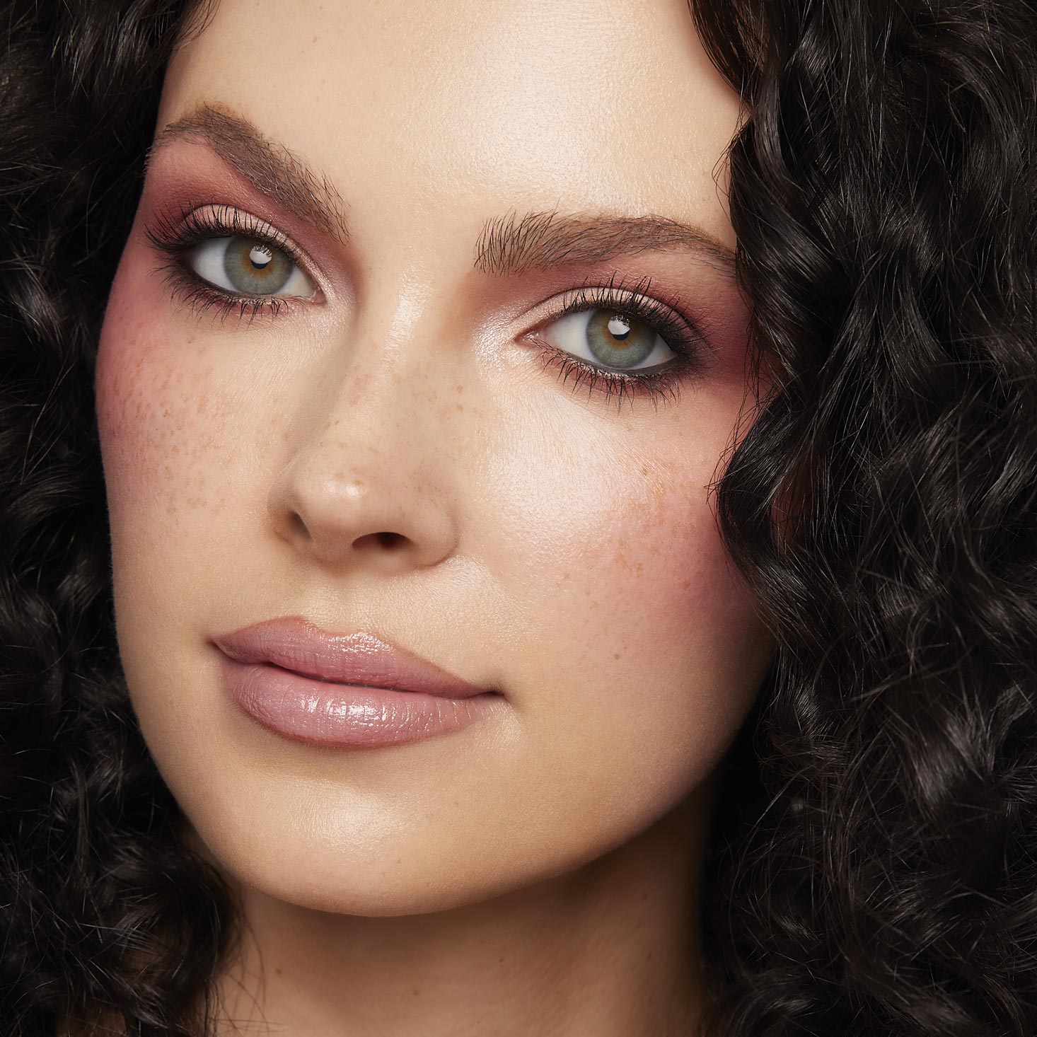 Close-up model wearing a rosy mauve eye look, blended shimmer and matte shades from the Blush Baby ColourPop Shadow Palette, with soft lashes, nude gloss lips, and natural freckles, shot in studio to showcase pigment payoff.